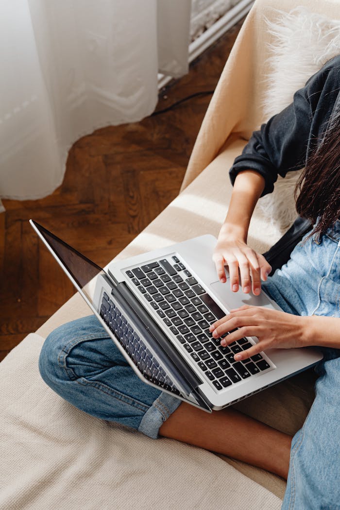 Home Young woman studying on a laptop at home, sitting on a couch, during the day.